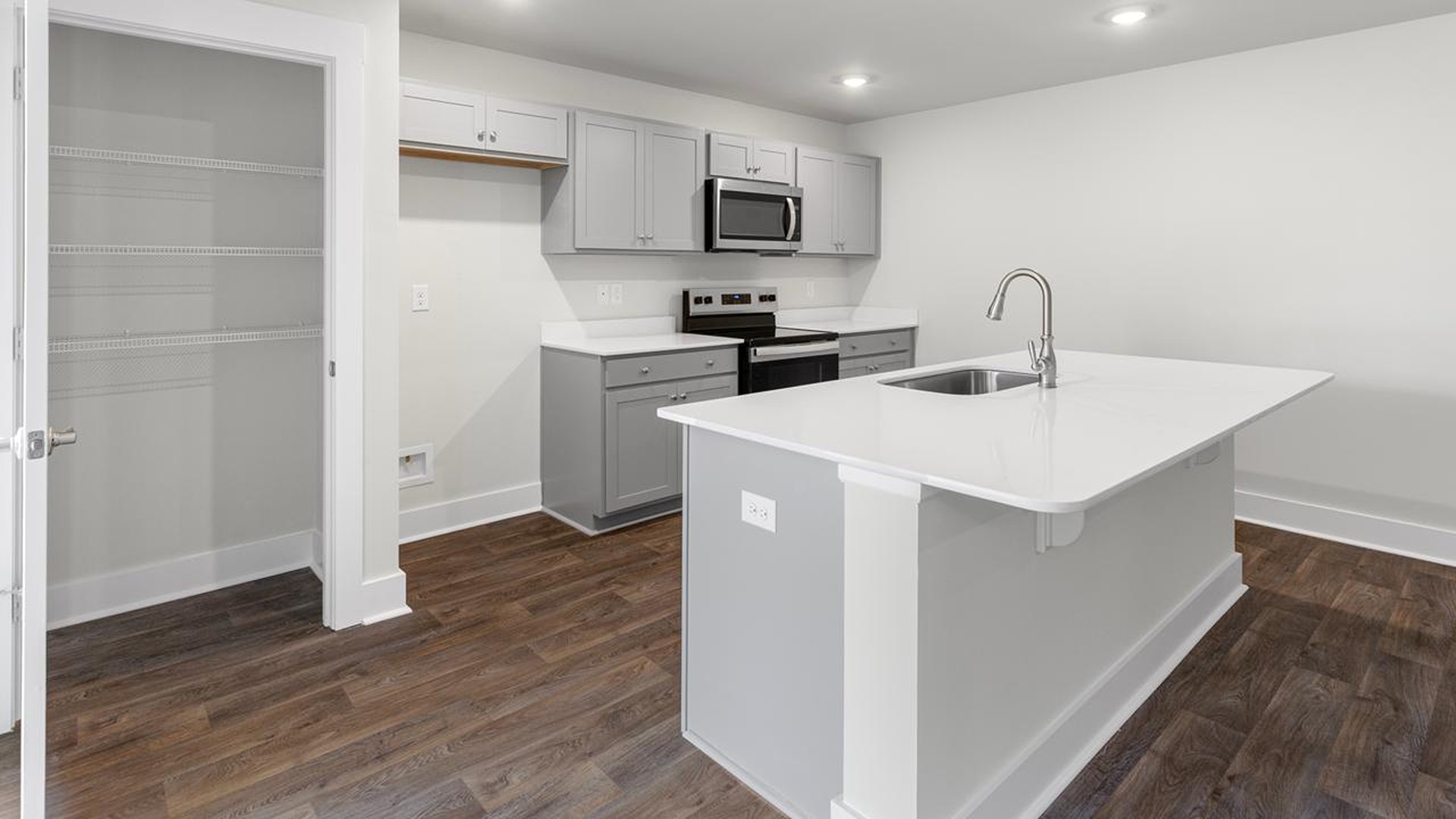 The open-concept family room, kitchen, and dining area feature granite countertops, stainless steel appliances, including a smooth-top range, dishwasher and overhead microwave.