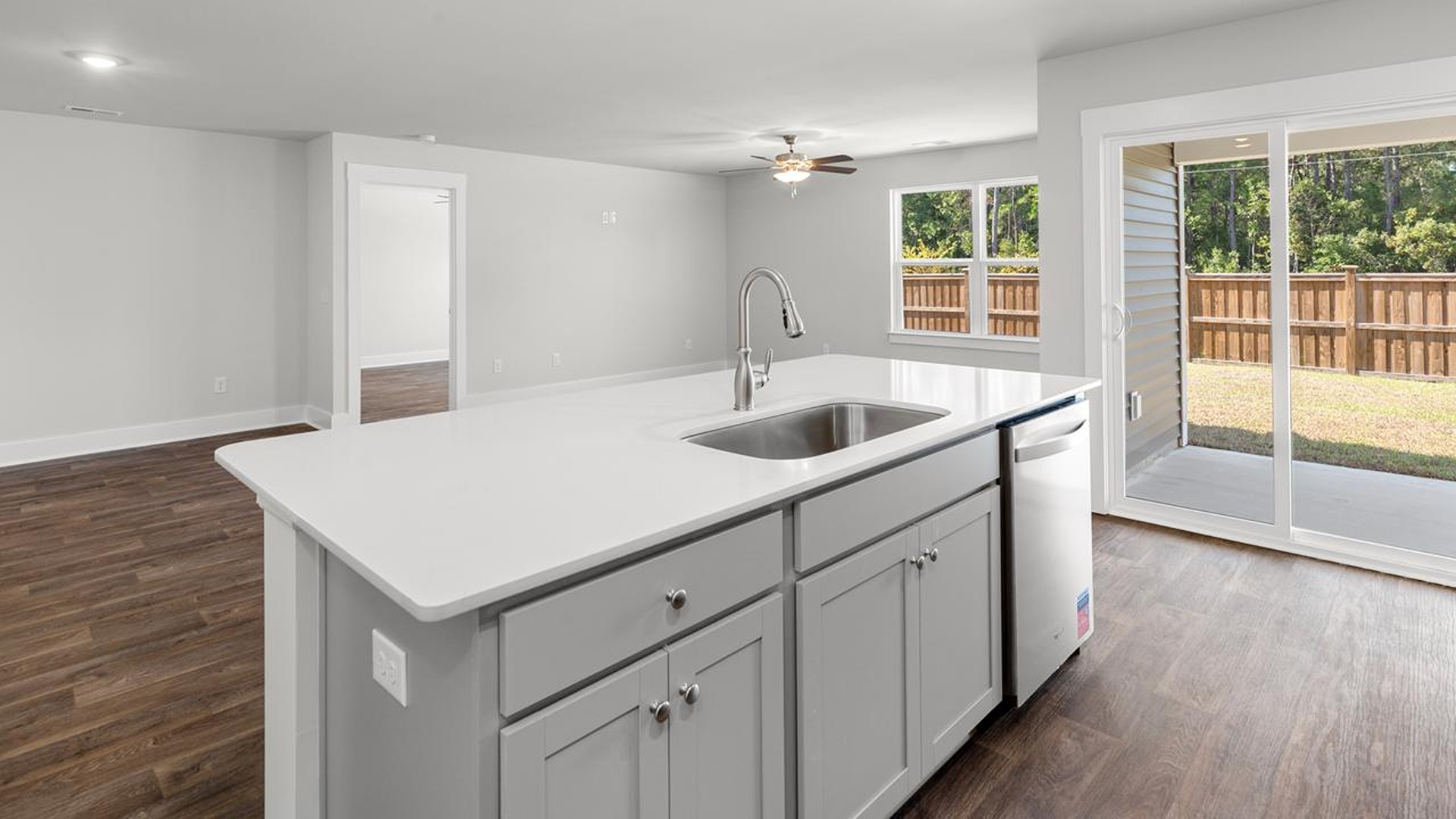 The open-concept family room, kitchen, and dining area feature granite countertops, stainless steel appliances, including a smooth-top range, dishwasher and overhead microwave.