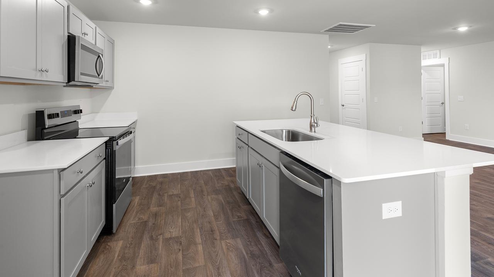 The open-concept family room, kitchen, and dining area feature granite countertops, stainless steel appliances, including a smooth-top range, dishwasher and overhead microwave.