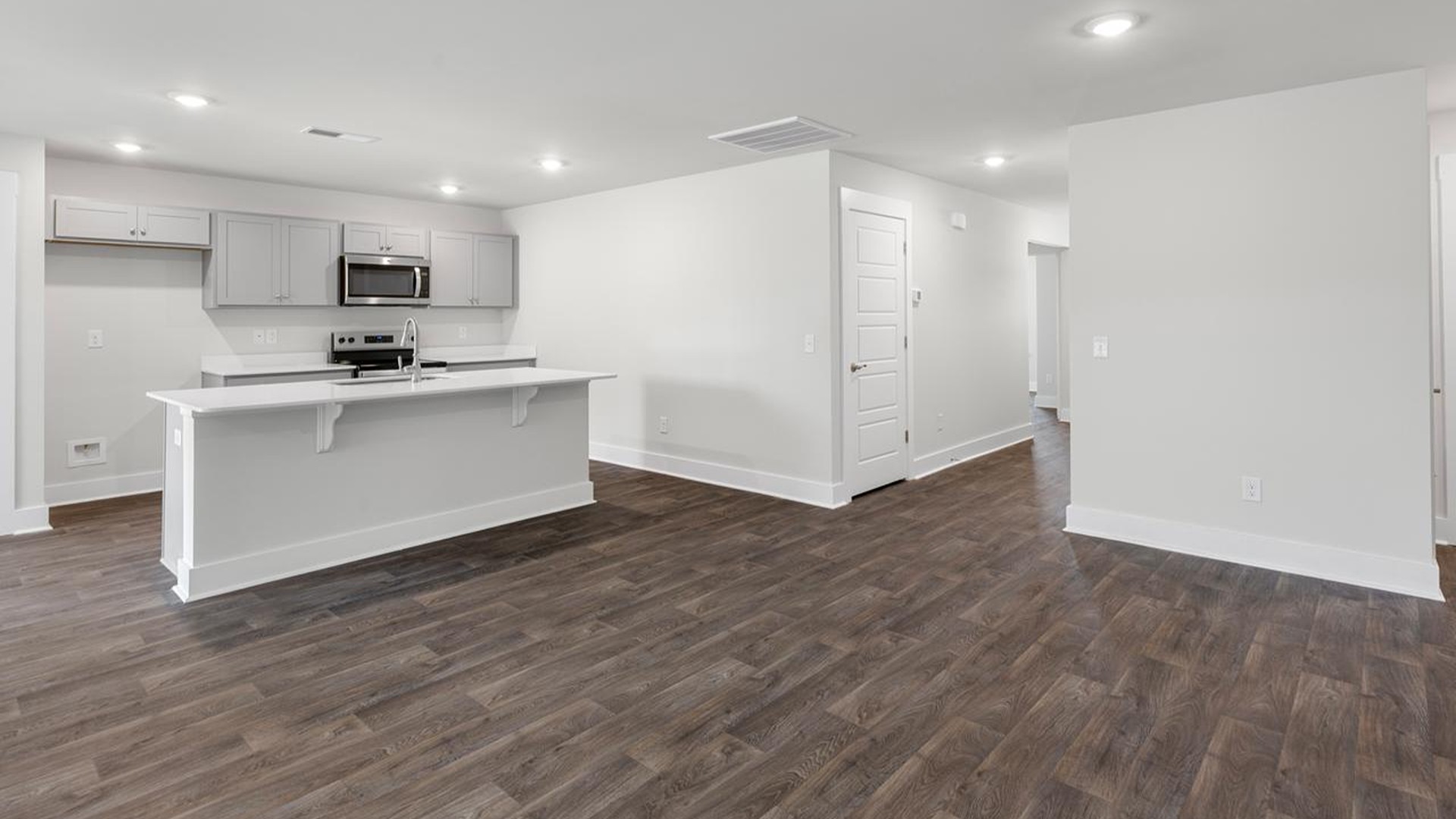The open-concept family room, kitchen, and dining area feature granite countertops, stainless steel appliances, including a smooth-top range, dishwasher and overhead microwave.