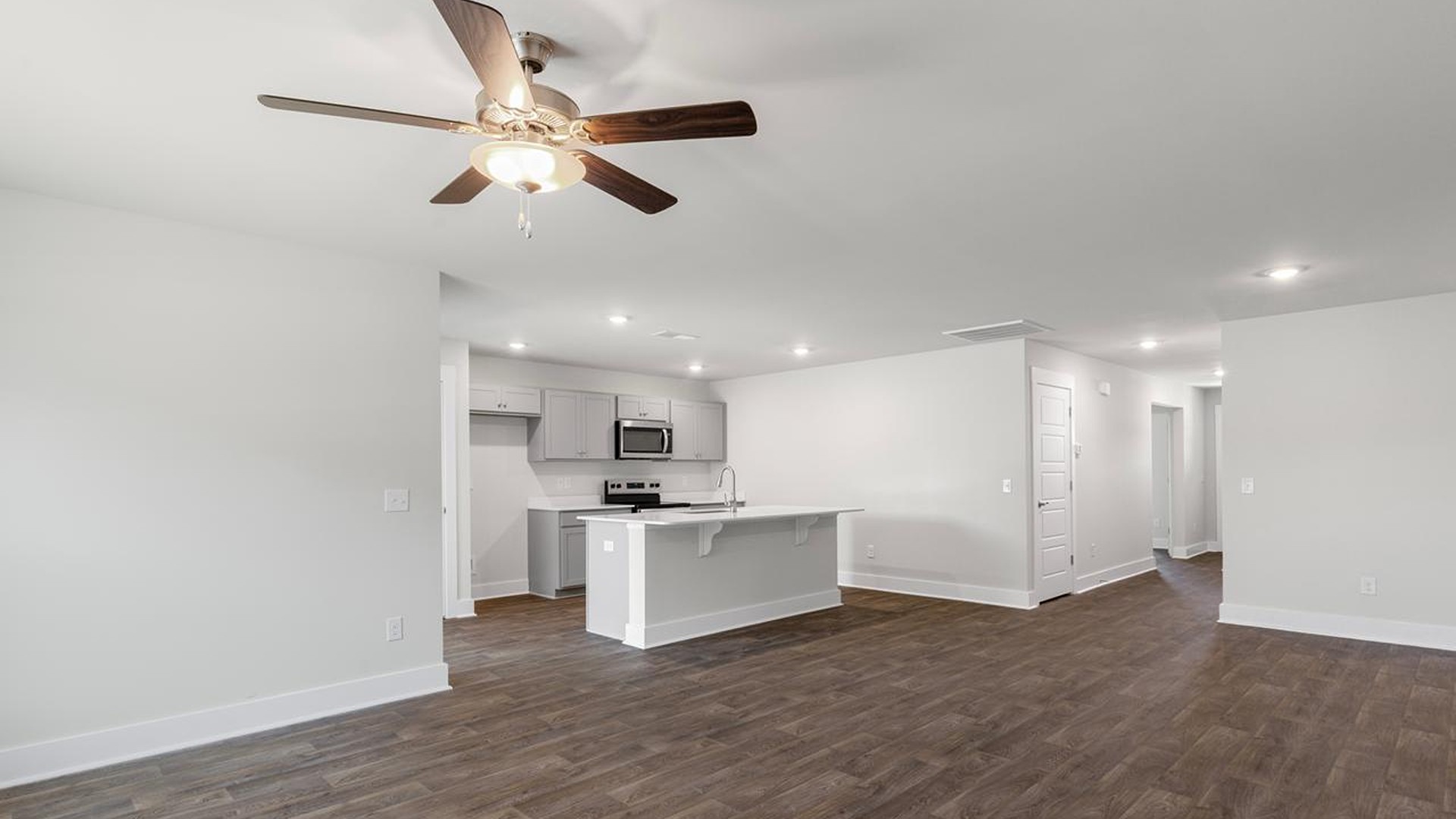 The open-concept family room, kitchen, and dining area feature granite countertops, stainless steel appliances, including a smooth-top range, dishwasher and overhead microwave.