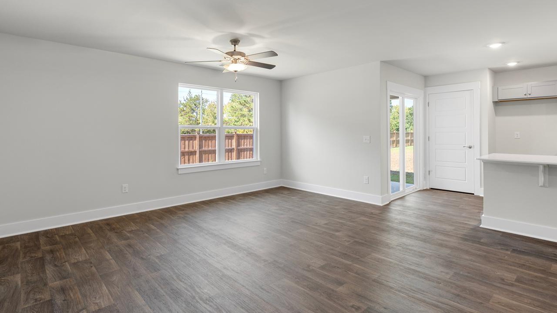 The open-concept family room, kitchen, and dining area feature granite countertops, stainless steel appliances, including a smooth-top range, dishwasher and overhead microwave.
