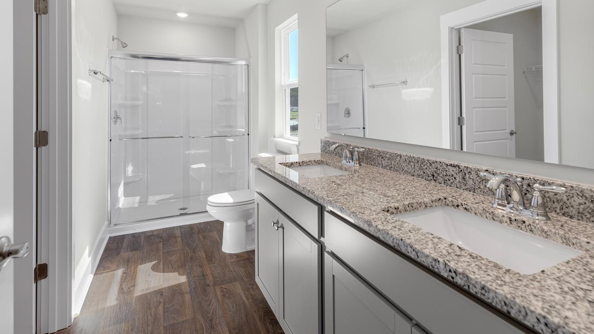 At the back, the primary suite provides privacy with a large walk-in closet and walk-in shower. This floor plan combines comfort and convenience, making it a great choice for those seeking an open layout and a 2-car garage.