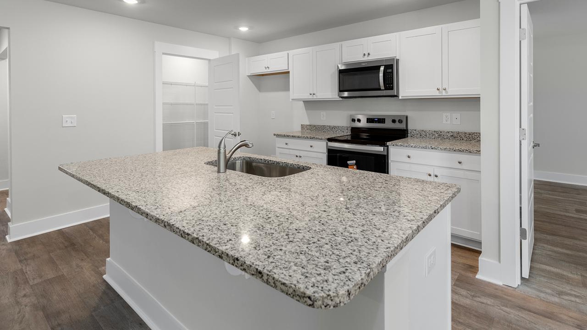 The kitchen features a large island, granite countertops, and stainless-steel appliances, which are sure to both turn heads and make meal prep easy.