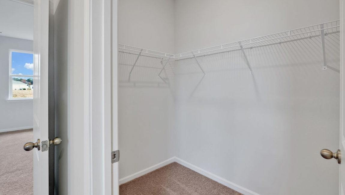 At the back, the Primary Suite provides privacy with a large walk-in closet and walk-in shower. This floor plan combines comfort and convenience, making it a great choice for those seeking an open layout.