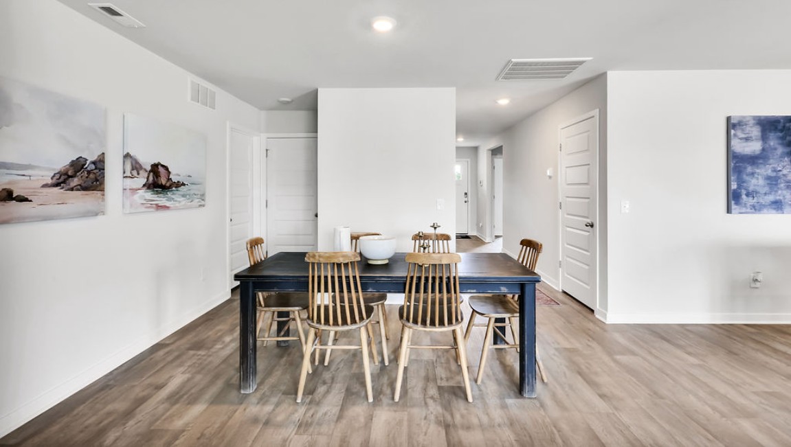 The open-concept family room, kitchen, and dining area feature granite countertops, stainless steel appliances, including a smooth-top range, dishwasher, and overhead microwave.