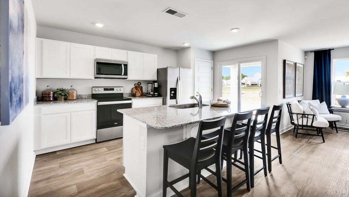 The open-concept family room, kitchen, and dining area feature granite countertops, stainless steel appliances, including a smooth-top range, dishwasher, and overhead microwave.