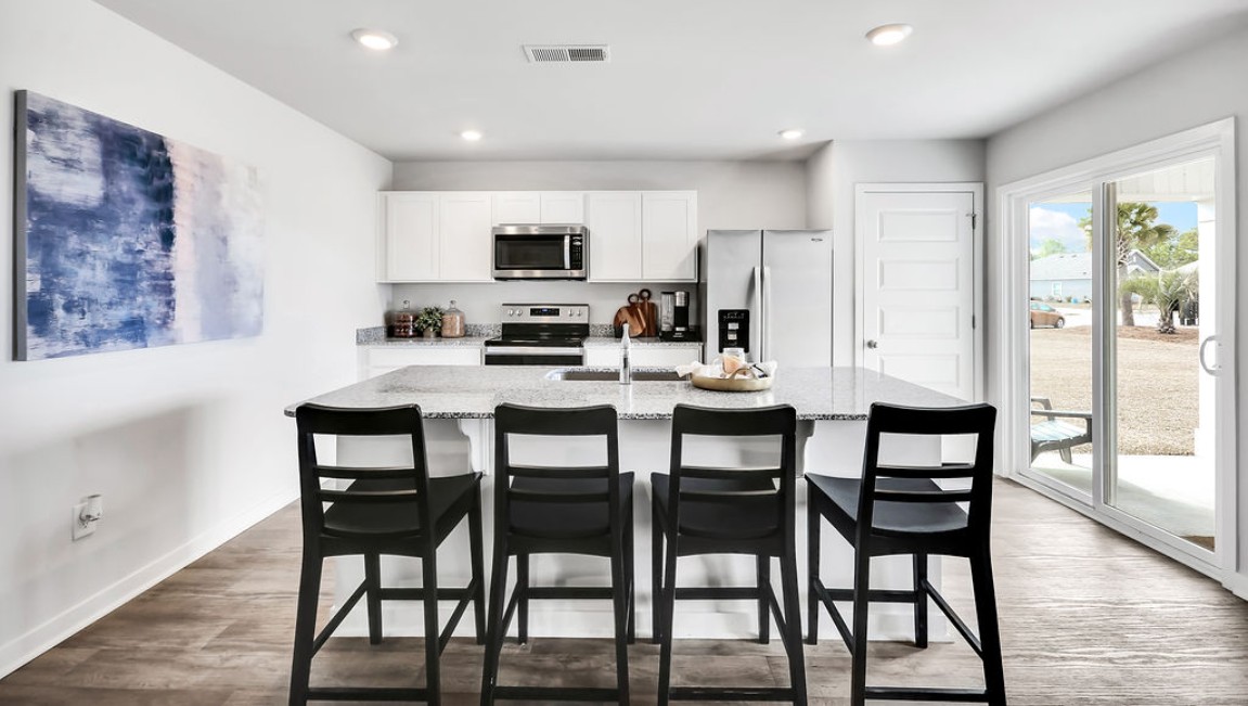 The open-concept family room, kitchen, and dining area feature granite countertops, stainless steel appliances, including a smooth-top range, dishwasher, and overhead microwave.