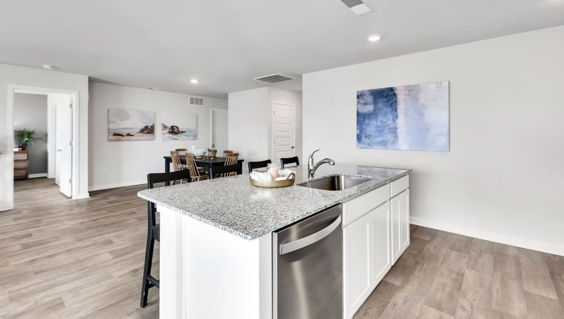 The open-concept family room, kitchen, and dining area feature granite countertops, stainless steel appliances, including a smooth-top range, dishwasher, and overhead microwave.