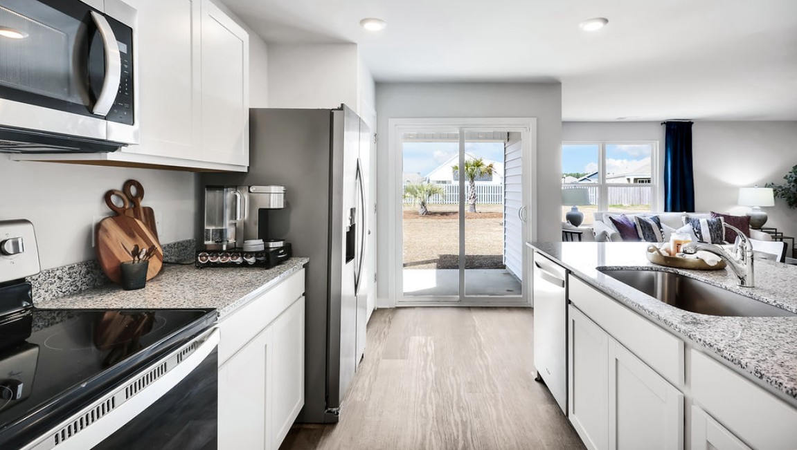 The open-concept family room, kitchen, and dining area feature granite countertops, stainless steel appliances, including a smooth-top range, dishwasher, and overhead microwave.