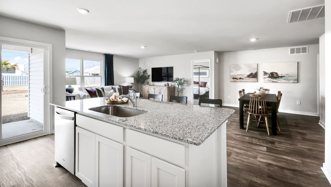 The open-concept family room, kitchen, and dining area feature granite countertops, stainless steel appliances, including a smooth-top range, dishwasher, and overhead microwave.