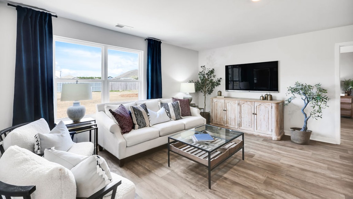 The open-concept family room, kitchen, and dining area feature granite countertops, stainless steel appliances, including a smooth-top range, dishwasher, and overhead microwave.