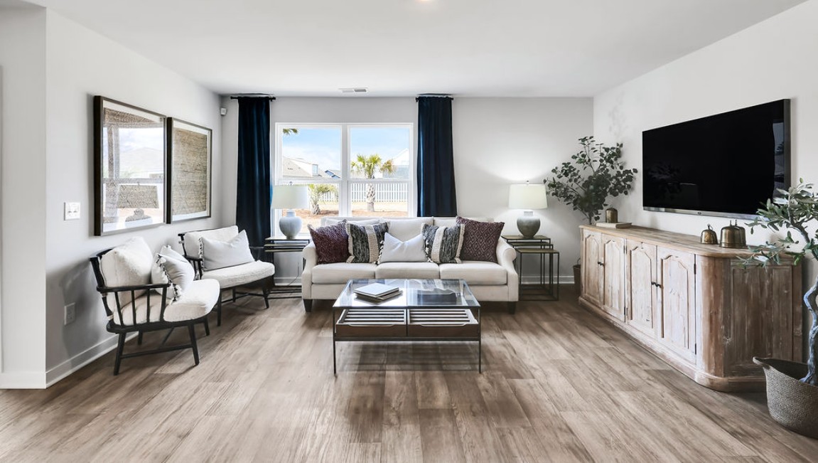 The open-concept family room, kitchen, and dining area feature granite countertops, stainless steel appliances, including a smooth-top range, dishwasher, and overhead microwave.