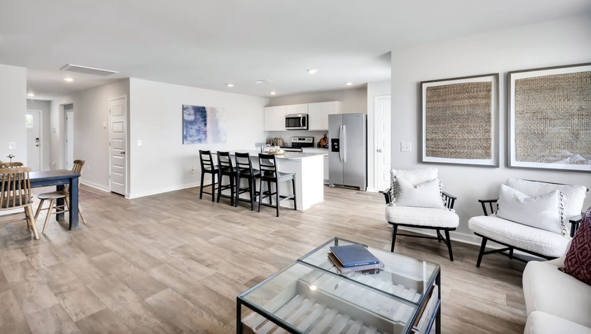The open-concept family room, kitchen, and dining area feature granite countertops, stainless steel appliances, including a smooth-top range, dishwasher, and overhead microwave.