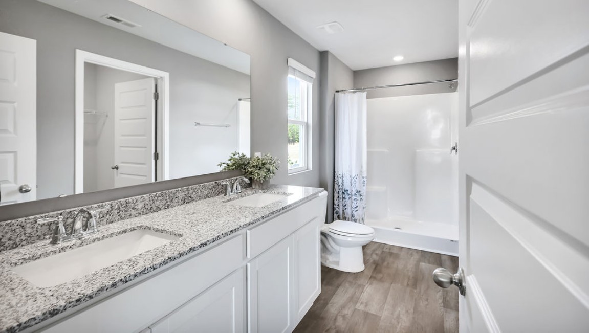At the back, the Primary Suite provides privacy with a large walk-in closet and walk-in shower. This floor plan combines comfort and convenience
