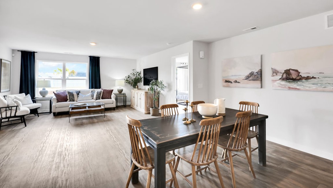 The open-concept family room, kitchen, and dining area feature granite countertops, stainless steel appliances, including a smooth-top range, dishwasher, and overhead microwave.