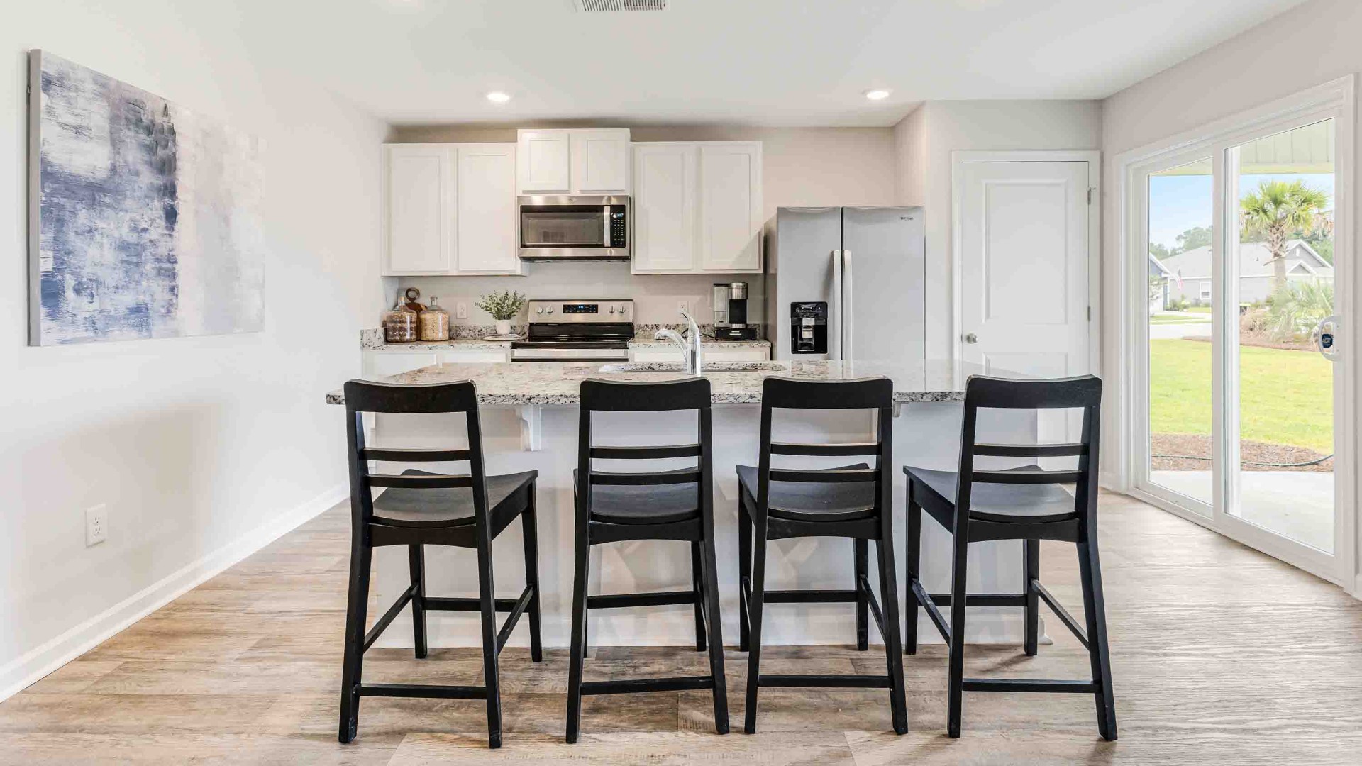 At the front are two guest bedrooms and a full bathroom, perfect for visitors or a home office. The open-concept family room, kitchen, and dining area feature granite countertops, stainless steel appliances, including a smooth-top range, dishwasher, and overhead microwave.