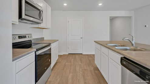The spacious kitchen offers plenty of cabinet and counter space with a large pantry and stainless steel appliances.
