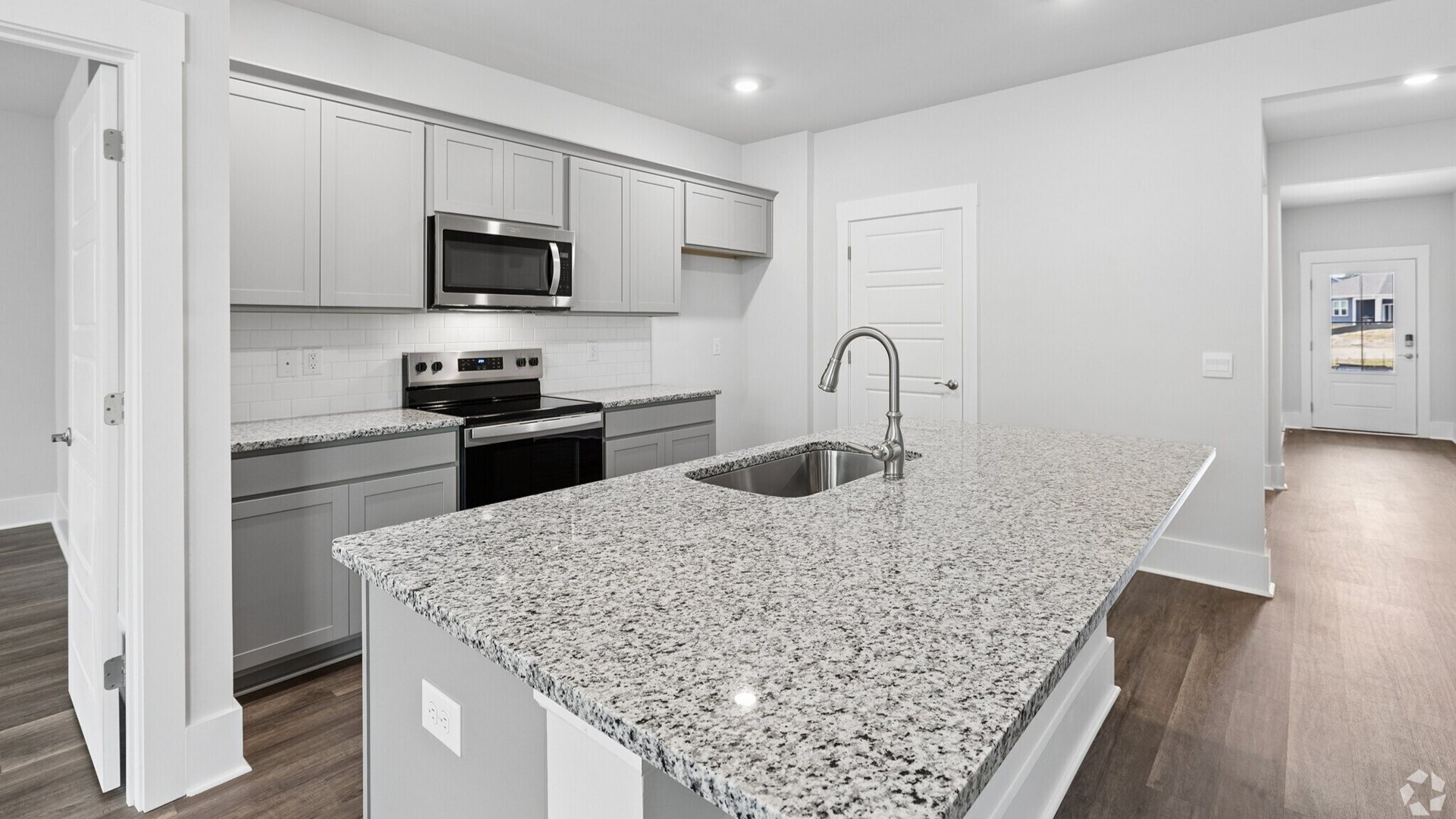 The kitchen features a large island, granite countertops, and stainless-steel appliances, which are sure to both turn heads and make meal prep easy.