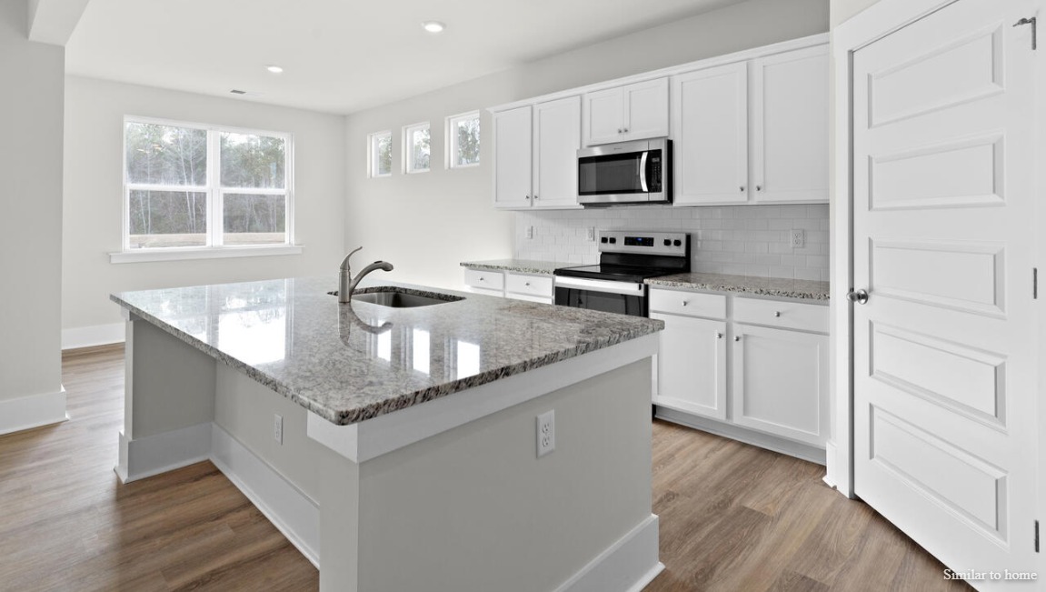 The kitchen boasts stainless steel appliances, a walk-in pantry, and a generous island that flows seamlessly into the main living area. D