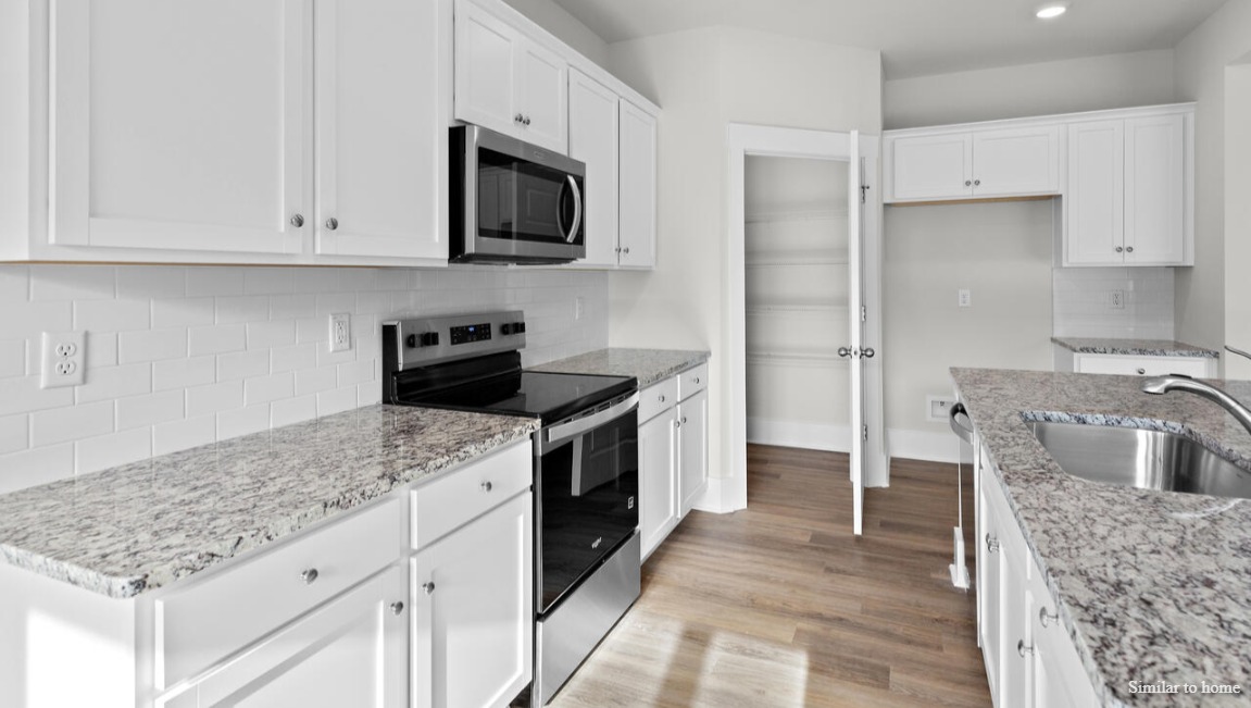 The kitchen boasts stainless steel appliances, a walk-in pantry, and a generous island that flows seamlessly into the main living area. D