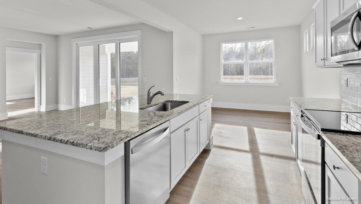 The kitchen boasts stainless steel appliances, a walk-in pantry, and a generous island that flows seamlessly into the main living area. D