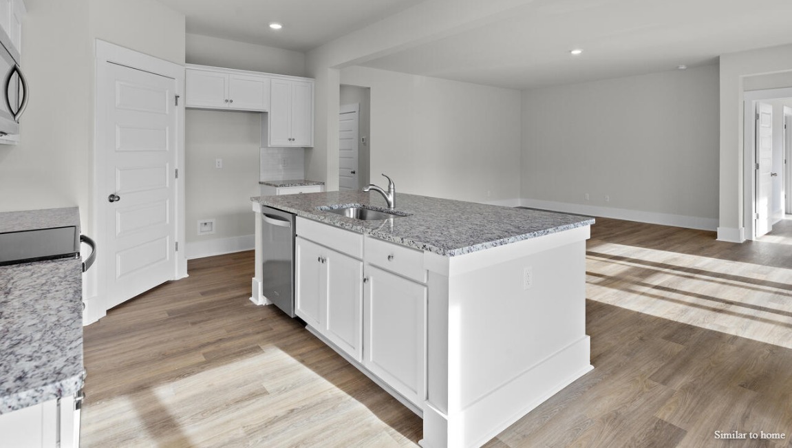 The kitchen boasts stainless steel appliances, a walk-in pantry, and a generous island that flows seamlessly into the main living area.