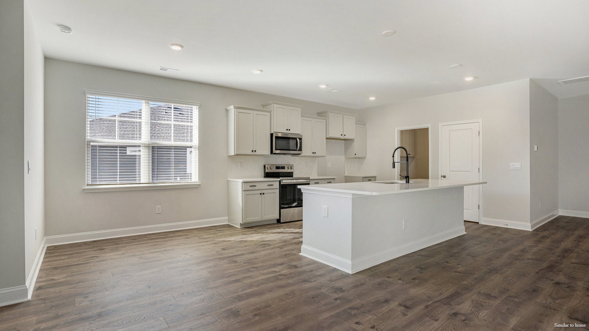 The kitchen features a central island and flows into a walk-in Pantry and a separate laundry room, which in turn connects to a storage area and the large three-car garage.