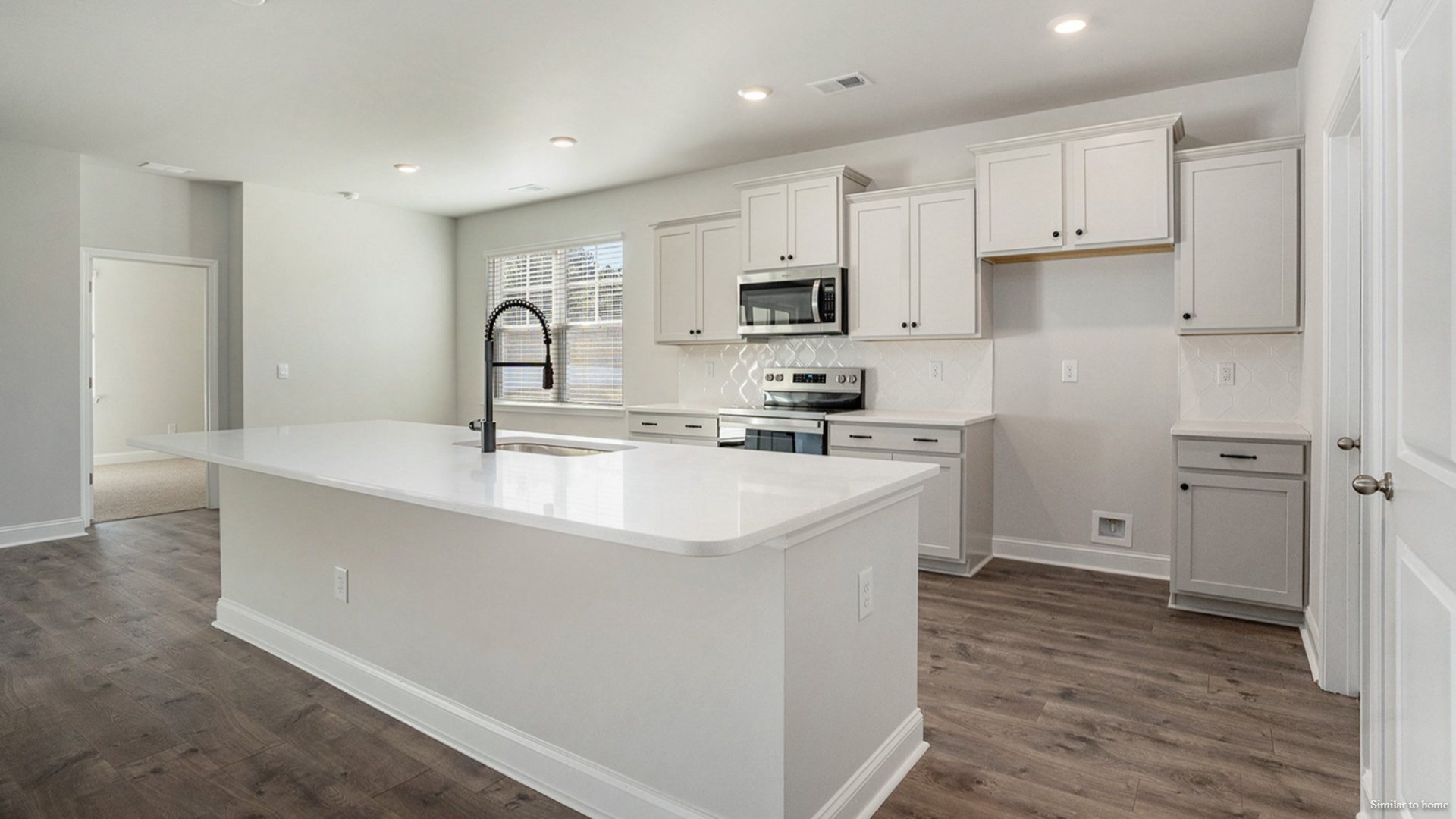 The kitchen features a central island and flows into a walk-in Pantry and a separate laundry room, which in turn connects to a storage area and the large three-car garage.