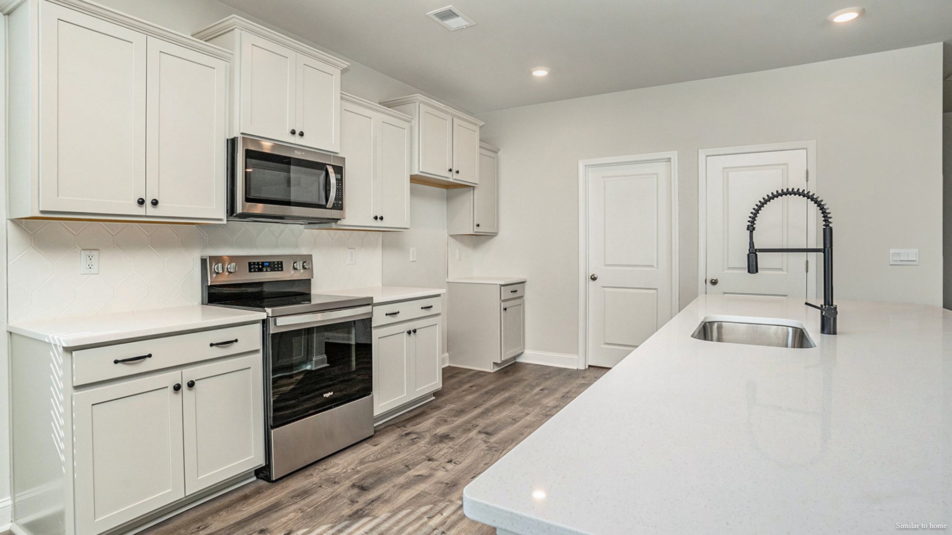 The kitchen features a central island and flows into a walk-in Pantry and a separate laundry room, which in turn connects to a storage area and the large three-car garage.