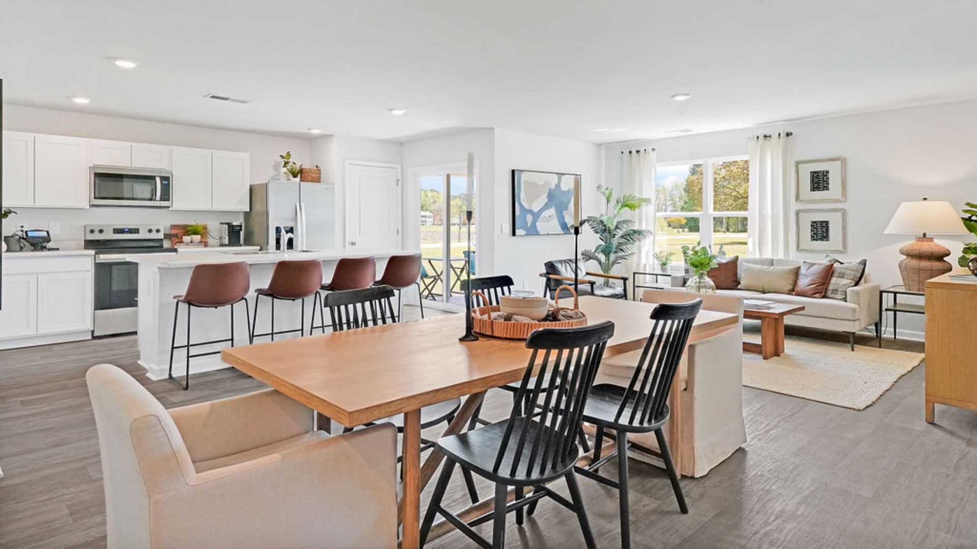 The open-concept family room, kitchen, and dining area feature stainless steel appliances, including a smooth-top range, dishwasher, and overhead microwave.