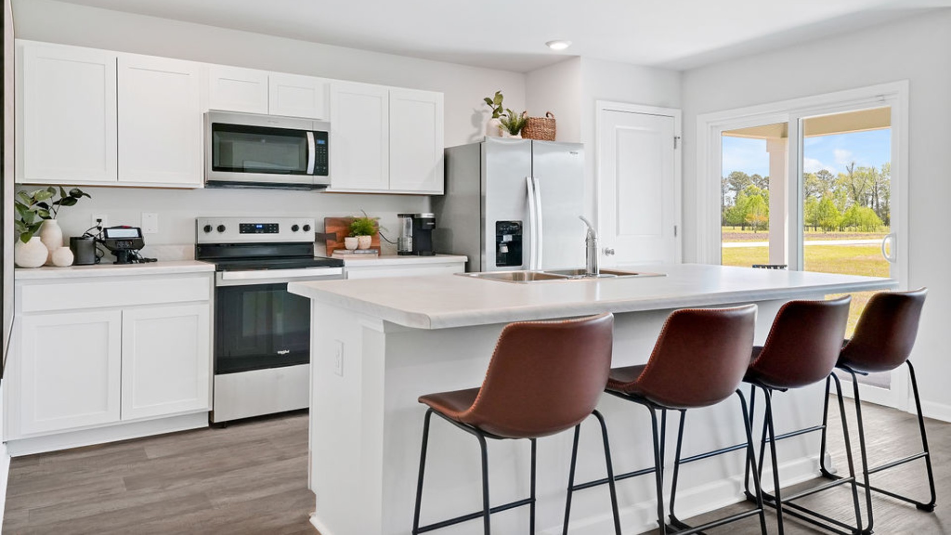 The open-concept family room, kitchen, and dining area feature stainless steel appliances, including a smooth-top range, dishwasher, and overhead microwave.