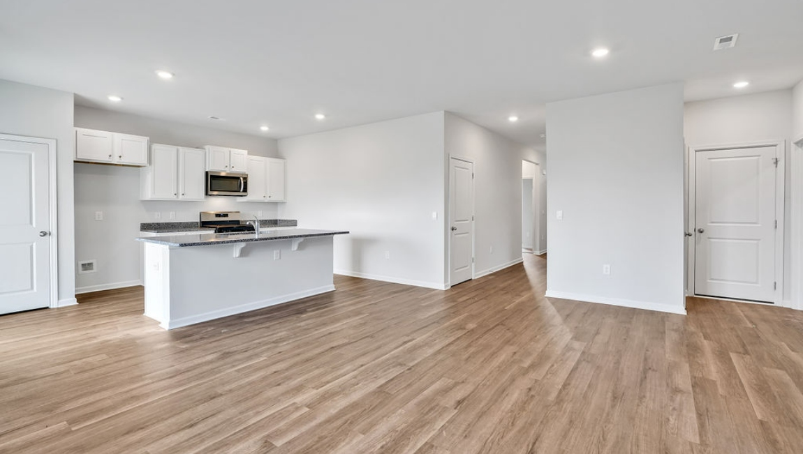 The open-concept family room, kitchen, and dining area feature stainless steel appliances, including a smooth-top range, dishwasher, and overhead microwave.