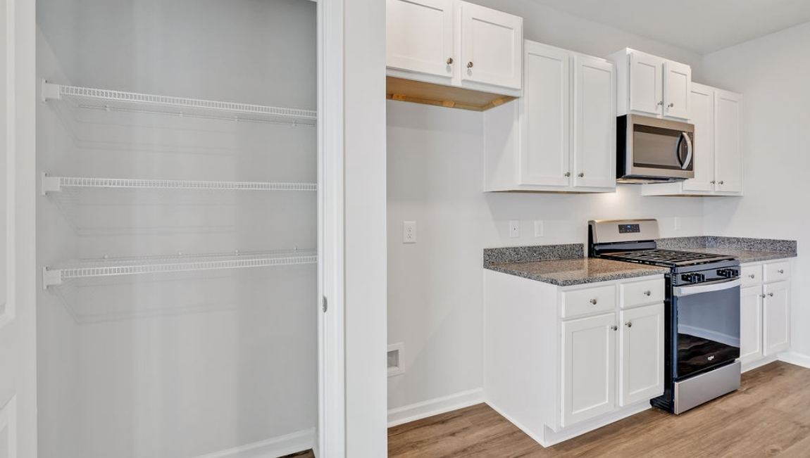 The open-concept family room, kitchen, and dining area feature stainless steel appliances, including a smooth-top range, dishwasher, and overhead microwave.