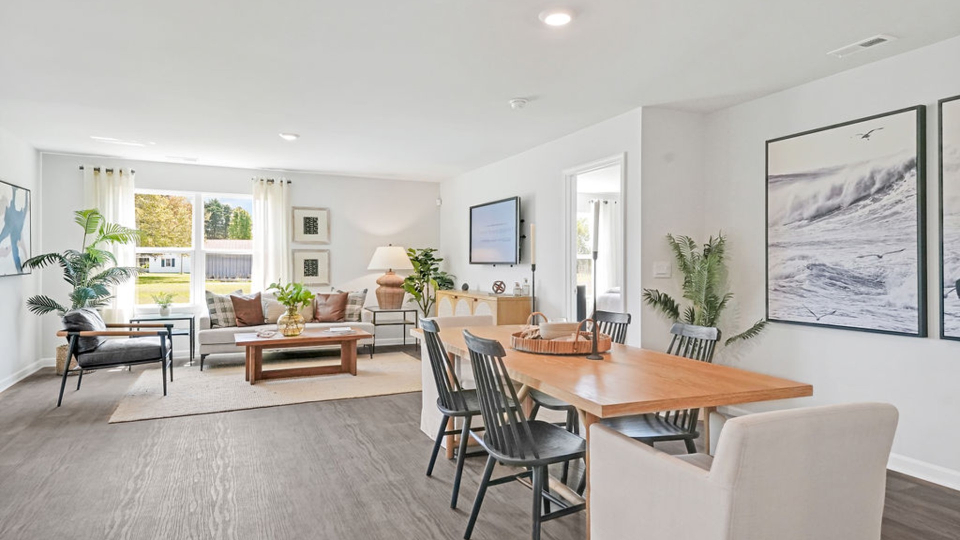 . The open-concept family room, kitchen, and dining area feature stainless steel appliances, including a smooth-top range, dishwasher, and overhead microwave.
