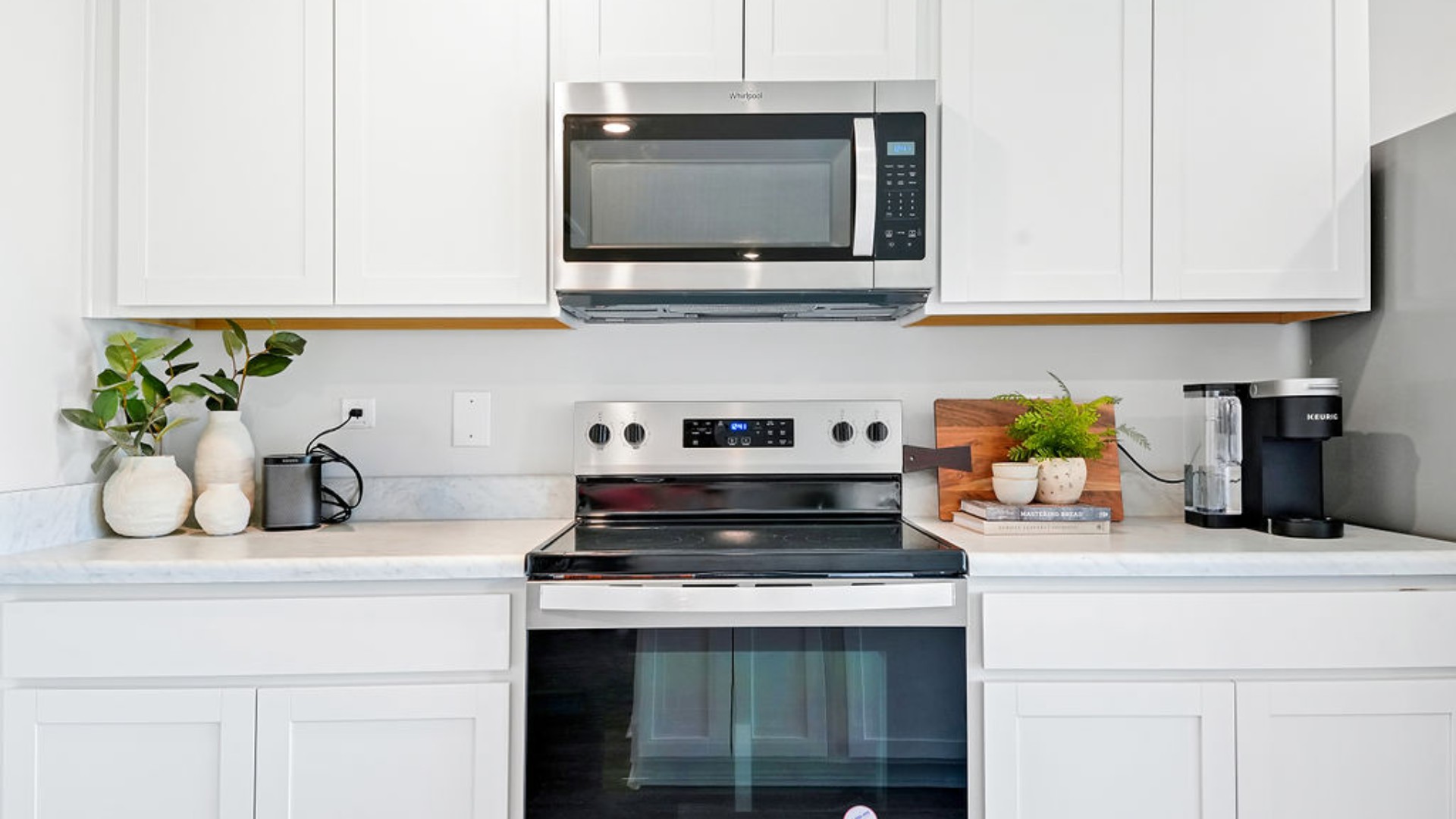 The open-concept family room, kitchen, and dining area feature stainless steel appliances, including a smooth-top range, dishwasher, and overhead microwave
