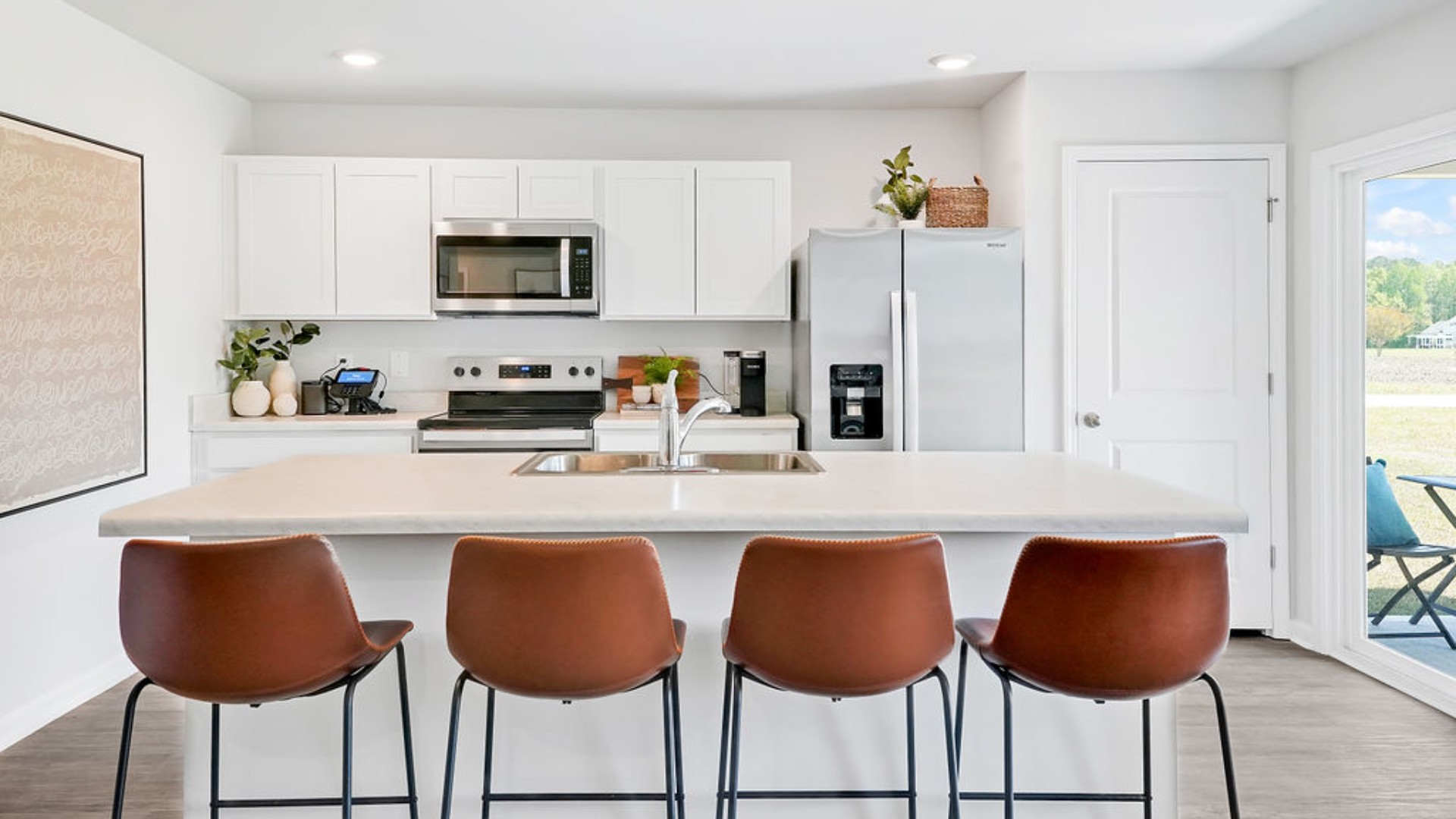 The open-concept family room, kitchen, and dining area feature stainless steel appliances, including a smooth-top range, dishwasher, and overhead microwave.