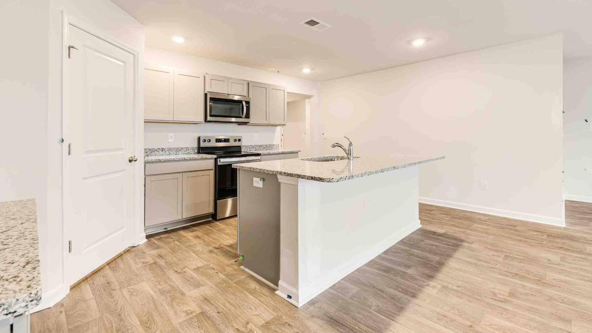 The kitchen features a large island, laminate countertops, and stainless steel appliances, which are sure to both turn heads and make meal prep easy