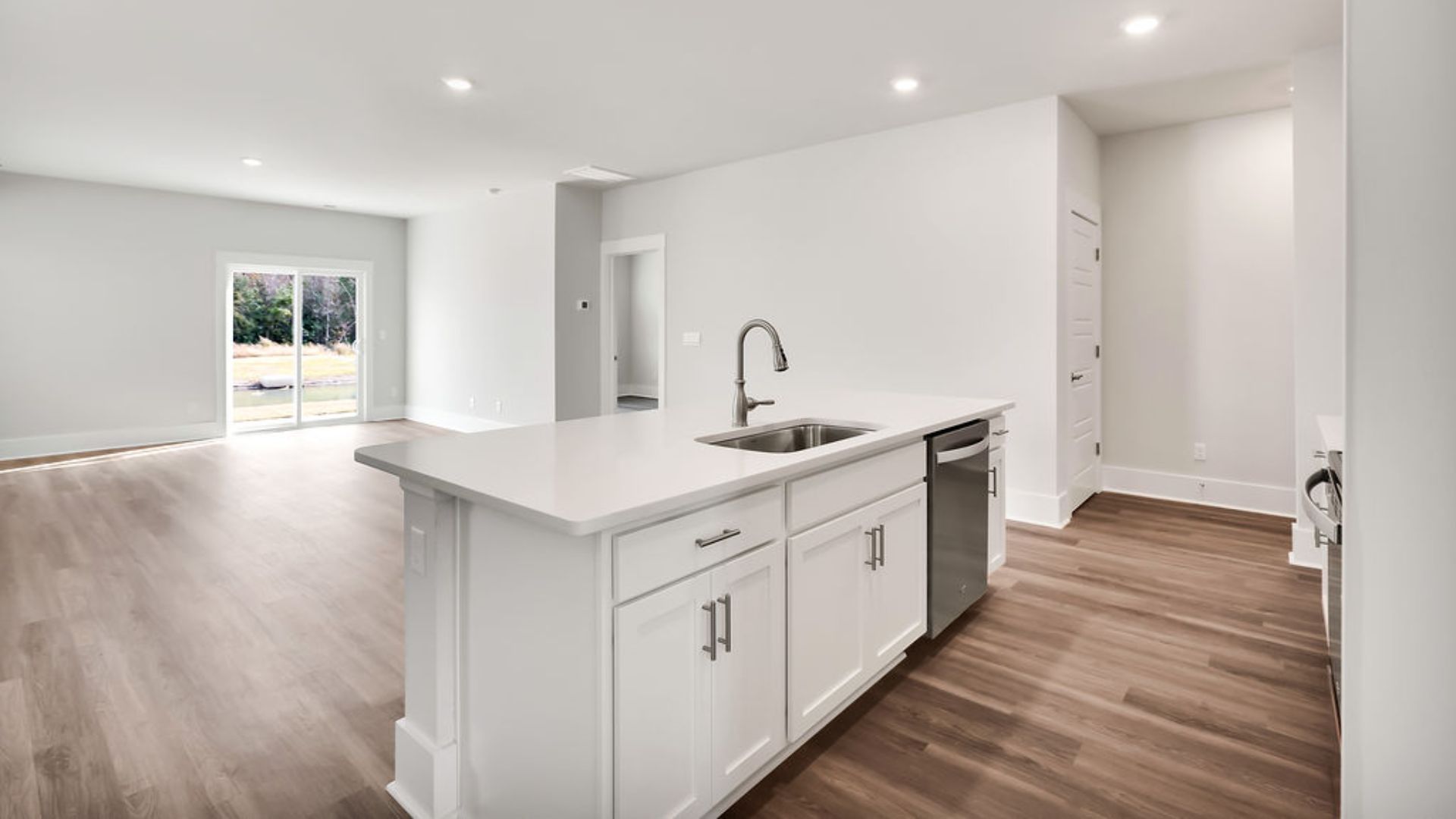 This beautiful kitchen features white cabinetry, granite counters, a large kitchen island with room for 4 counter height barstools and there's a pantry too. You’ll never be too far from the action with the living and dining area right there.