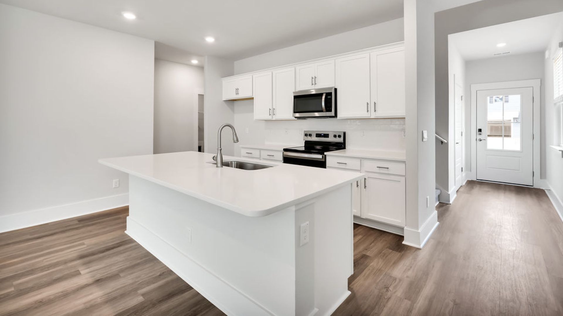 This beautiful kitchen features white cabinetry, granite counters, a large kitchen island with room for 4 counter height barstools and there's a pantry too. You’ll never be too far from the action with the living and dining area right there.