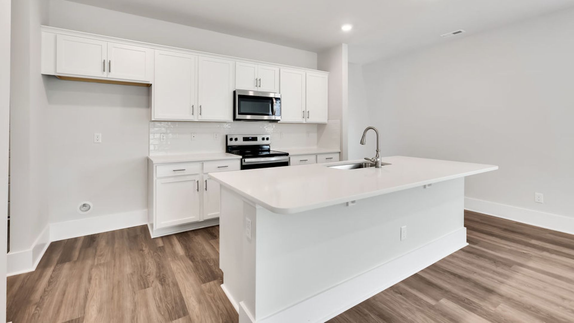 This beautiful kitchen features white cabinetry, granite counters, a large kitchen island with room for 4 counter height barstools and there's a pantry too. You’ll never be too far from the action with the living and dining area right there.