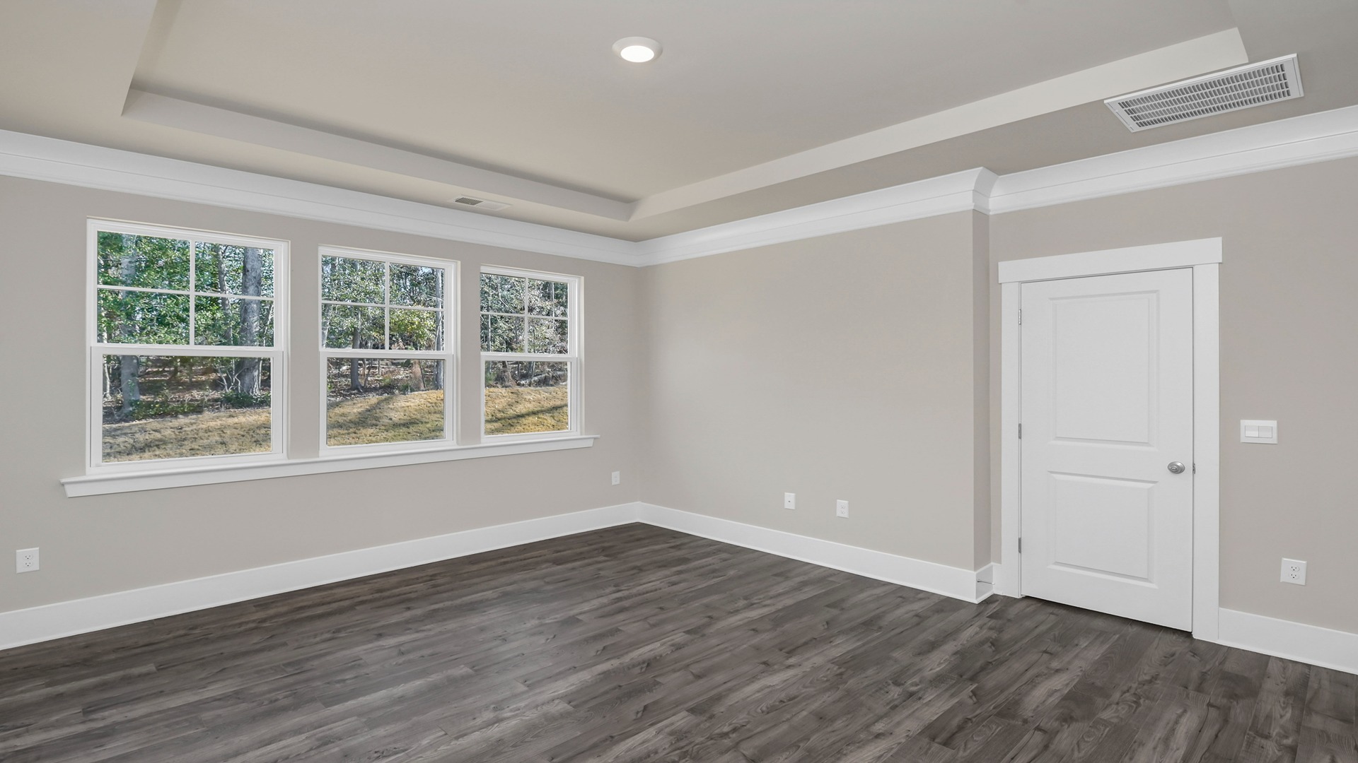 Several windows and Revwood flooring in primary bedroom