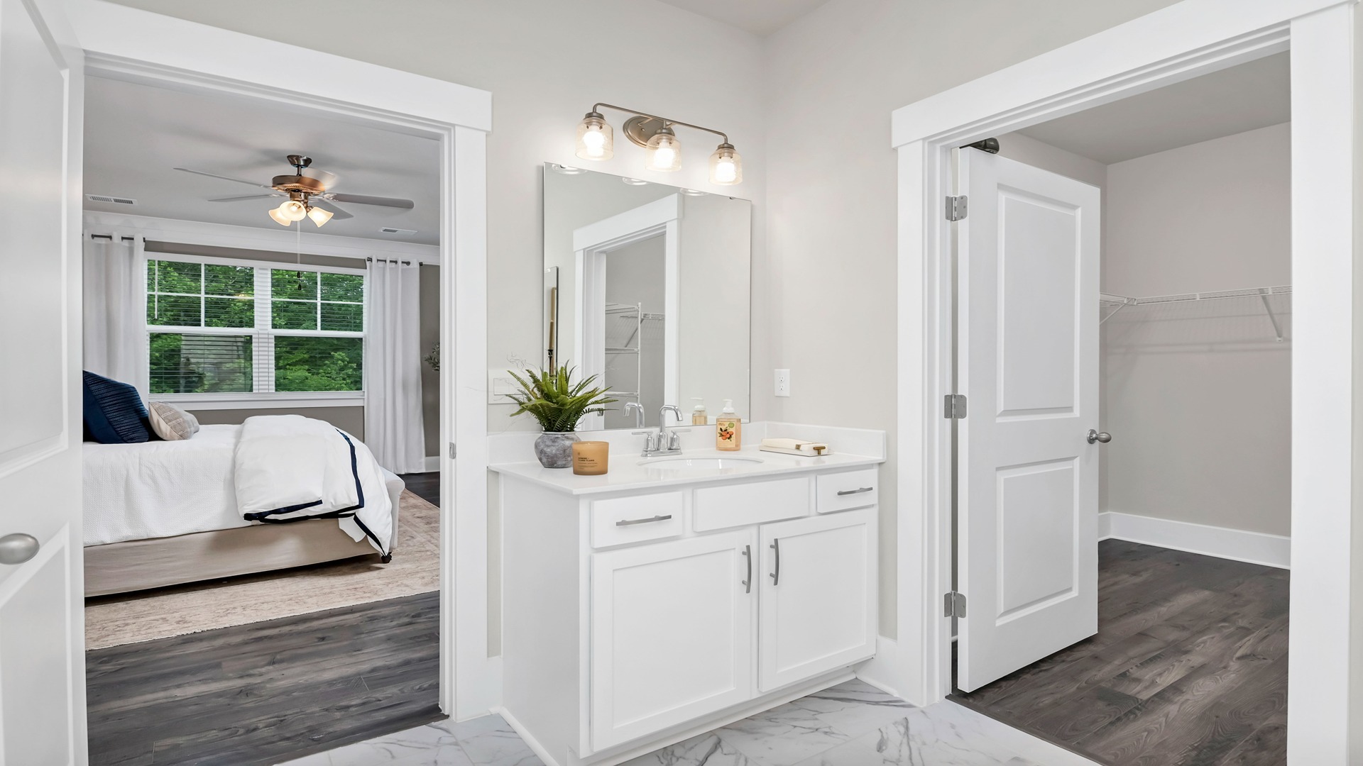 The primary bathroom features white cabinetry and a private walk-in closet.