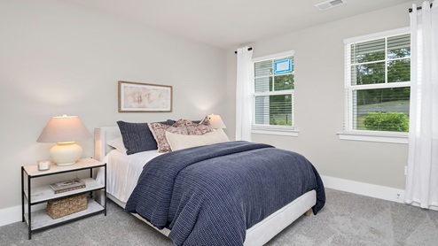 Downstairs bedroom carpeted with several window for natural light.