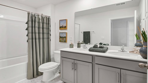 Bathroom 2 with double sinks and gray cabientry.