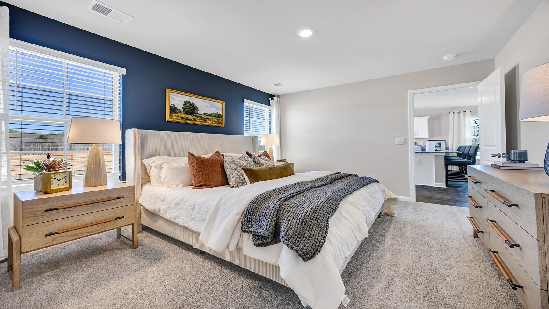 Large primary bedroom with two windows and carpet floors