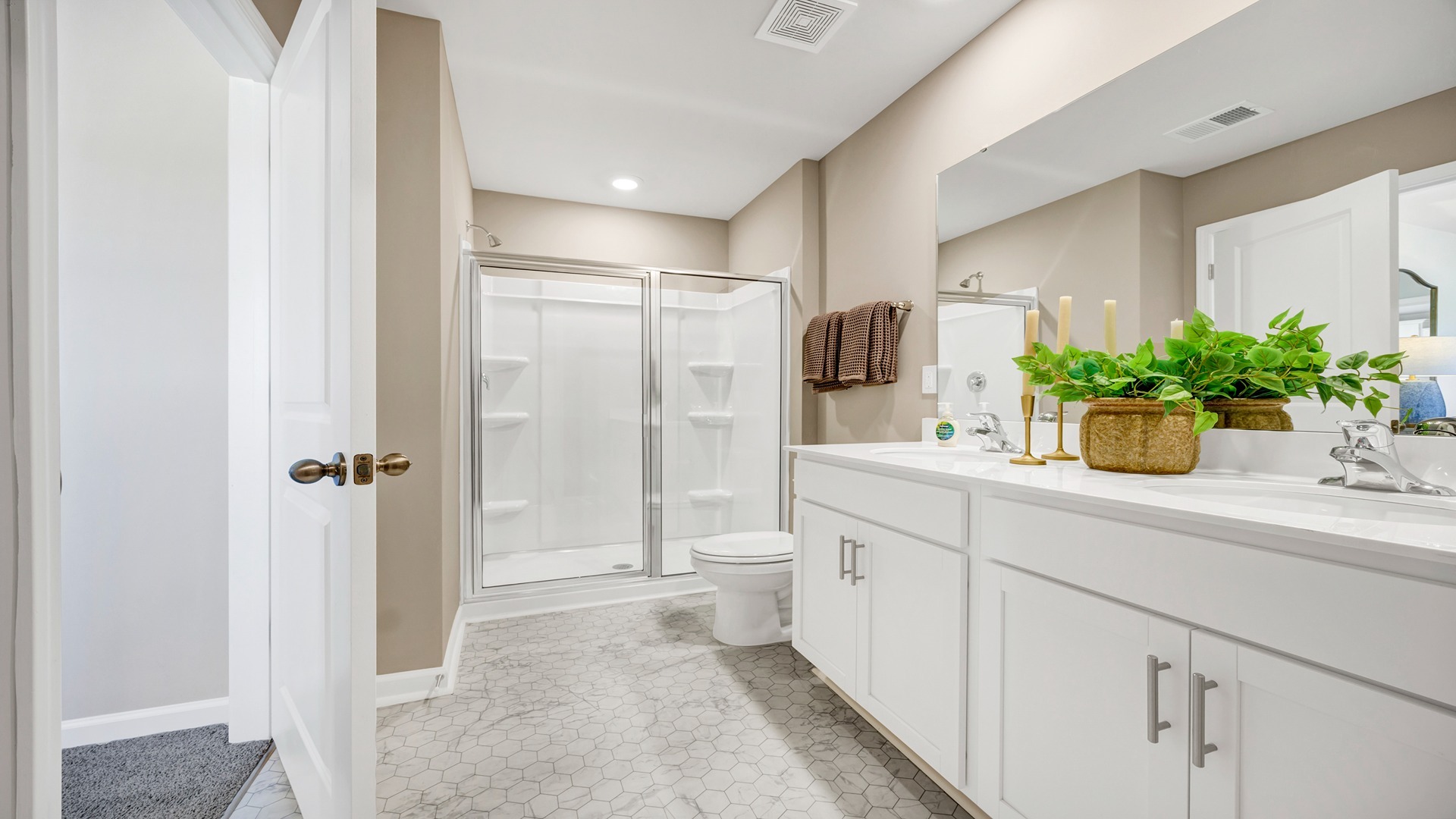 Walk-in primary shower in primary bathroom with double vanity and quartz countertops
