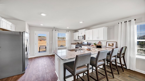 This furnished Curtis Kitchen features white cabinetry and granite countertops.