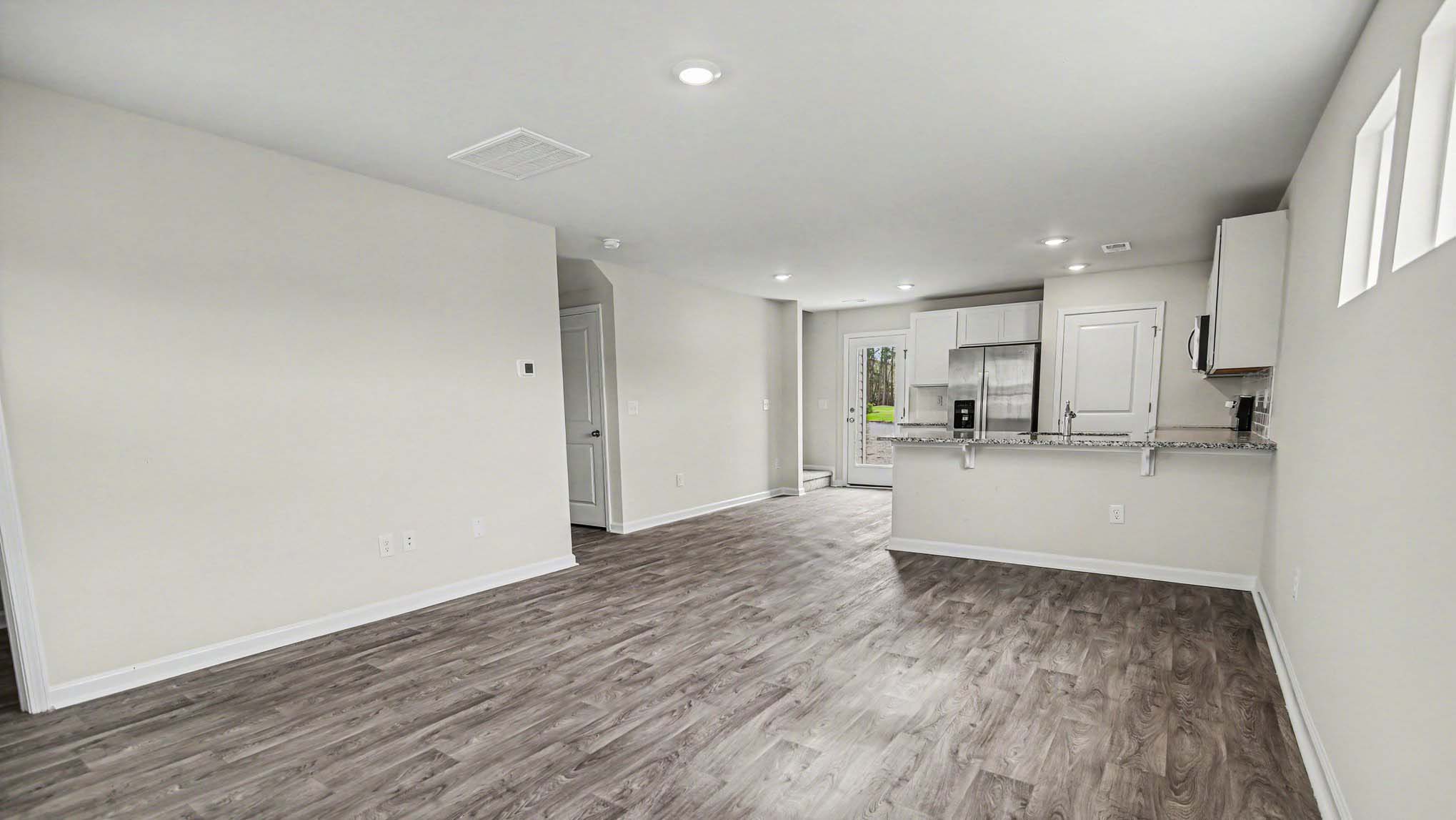 Open kitchen and living areas with matching vinyl floors in home for sale in Orangeburg, SC