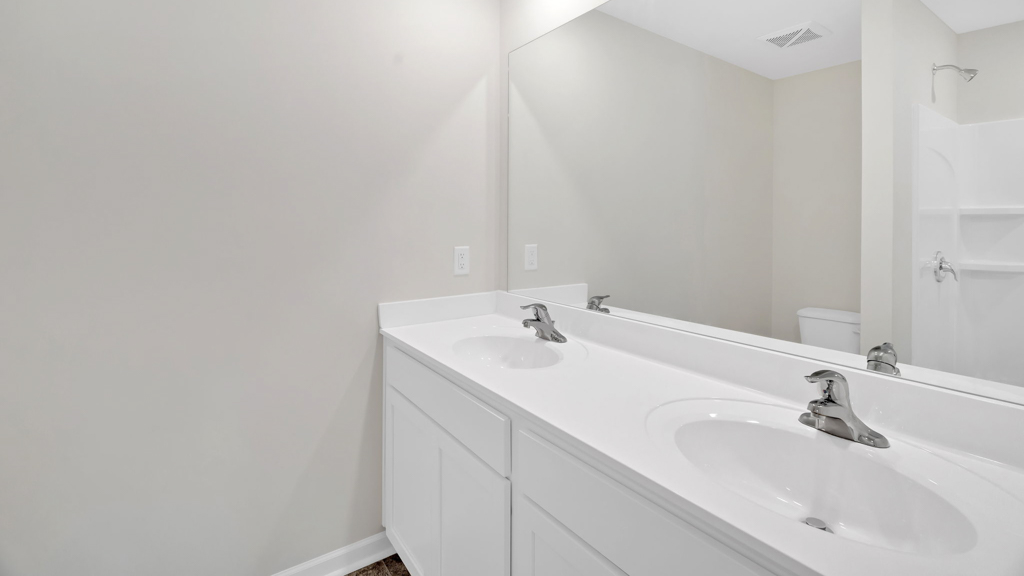 Primary bathroom with double vanity and white cabinetry